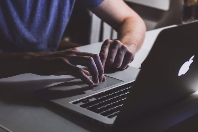 person touching open macbook on table